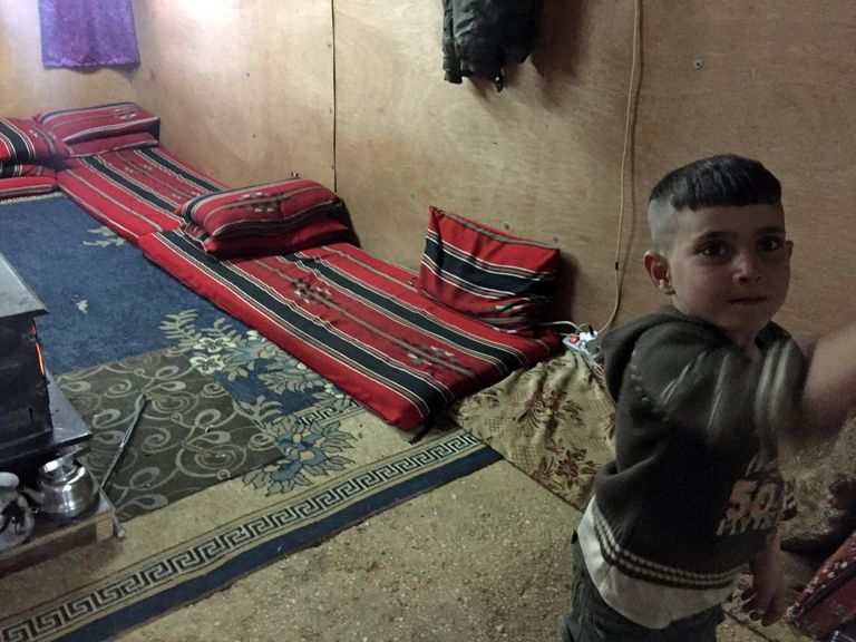 Kaheksaliikmelise süüria põgenike pere elupaik Bekaa orus: madratsid seinte ääres, keskel raudahi.