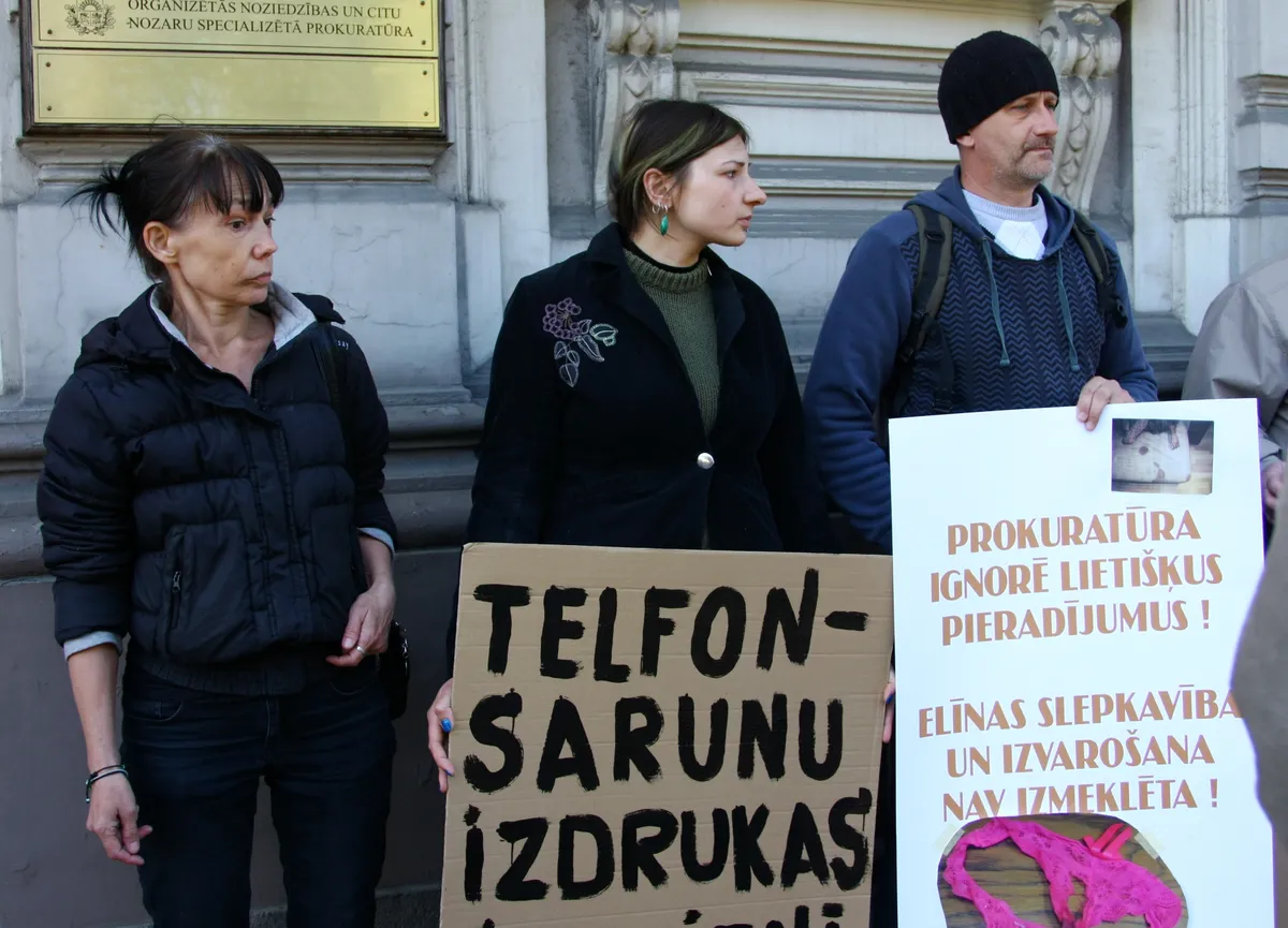 Noslepkavotās jaunietes māte Aija Pupiņa (no kreisās) un māsa piedalās piketā pie Ģenerālprokuratūras ēkas pret iespējamo pierādījumu slēpšanu studentes Elīnas Pupiņas slepkavības lietā.