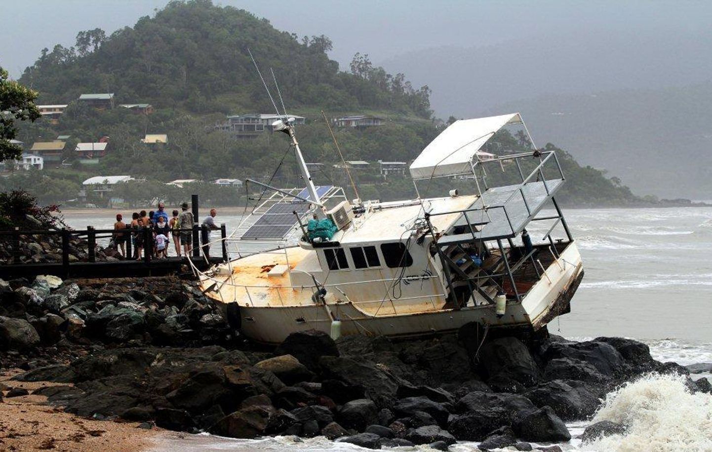 Inimesed uurivad paati, mis troopilise tsükloni Oswaldi tegutsemise tulemusel lendas kividele Airlie rannas, mis asub 120 km Townsville'st (Queenslandi osariik) kagus.