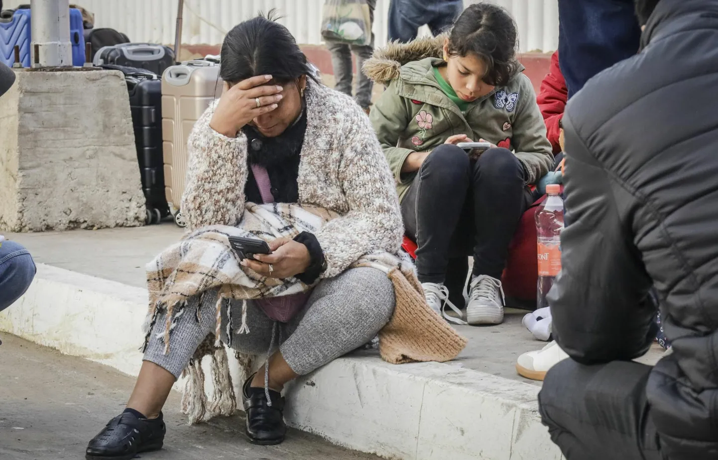 Migrandid, kelle vestlus varjupaiga saamiseks USAs tühistati, otsivad Mehhiko piirilinnas Tijuanas nutitelefonist uut infot.