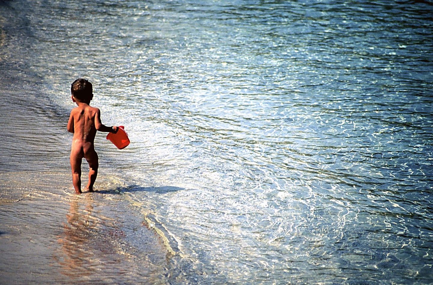 Paljas laps rannas.