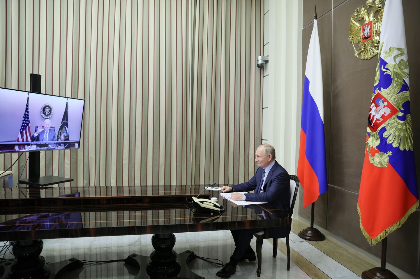 Venemaa president Vladimir Putin vaatab teleriekraanilt lehvitavat USA kolleegi Joe Bidenit.