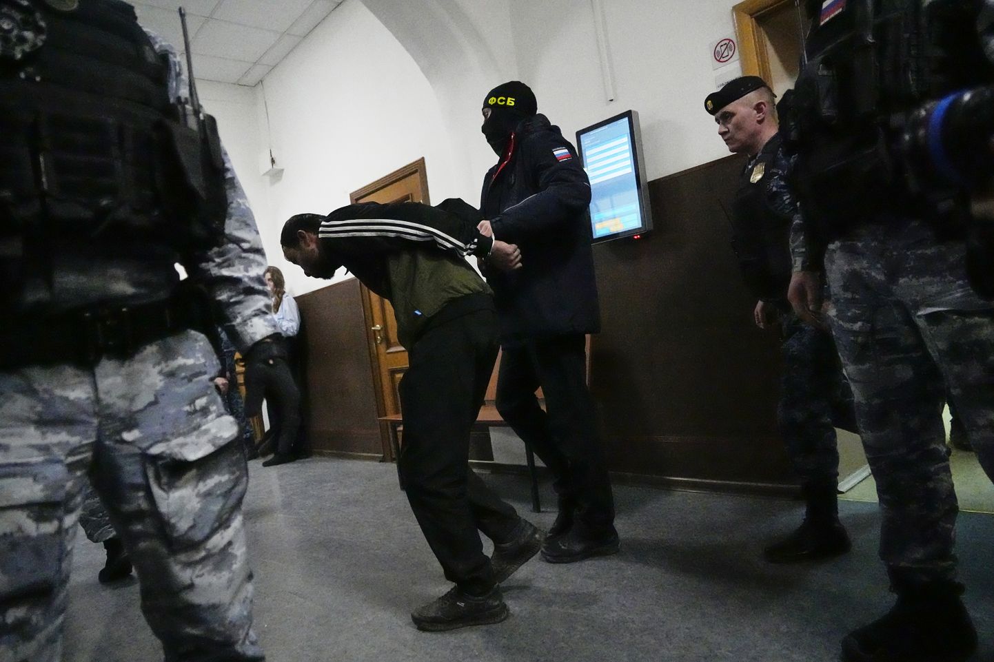 Venemaa Föderatsiooni Föderaalse Julgeolekuteenistuse (FSB) ametnik eskortimas ühte Moskva kontserdisaali terrorirünnaku toimepaneku kahtlusalustest kohtusaali 25. märtsil 2024. aastal.