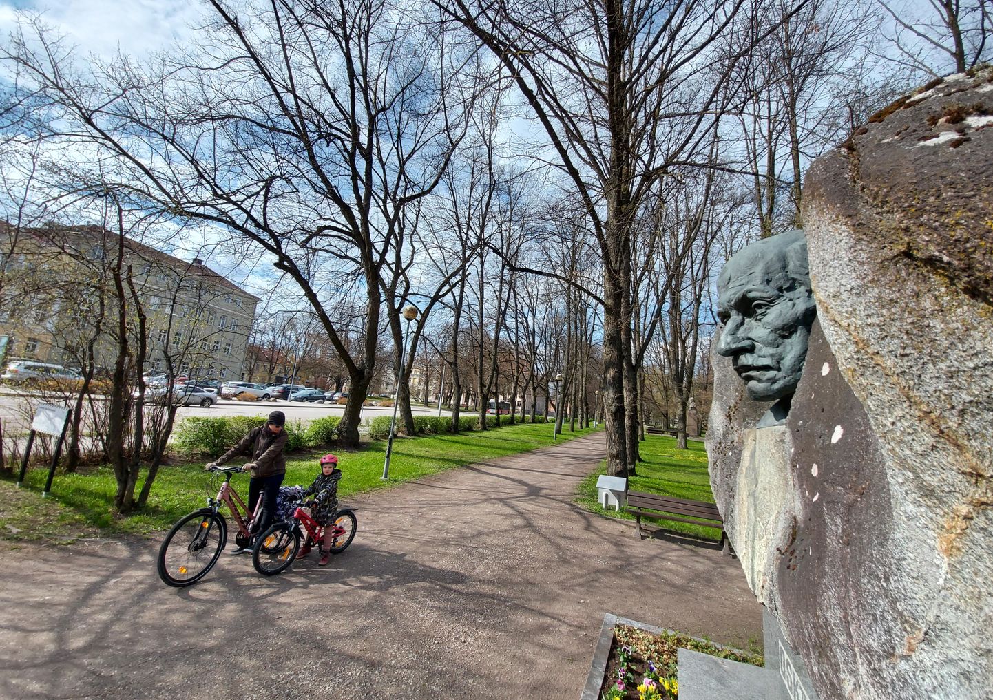 Tartu linnaraamatukogu (vasakul) lähedal Emajõe kaldapargis asub Oskar Lutsu skulptuur, mille autorid on skulptor Aulin Rimm ja arhitekt Allan Murdmaa.