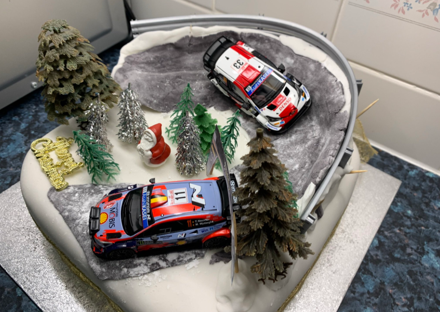 Ralliteemaline jõulukook, mida ilustavad ralliautode mudelid.