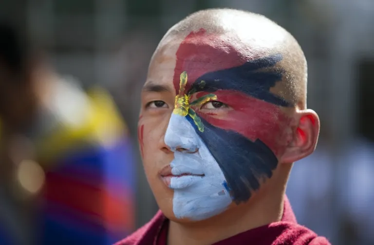 Монах раскрасил лицо в цвета тибетского флага