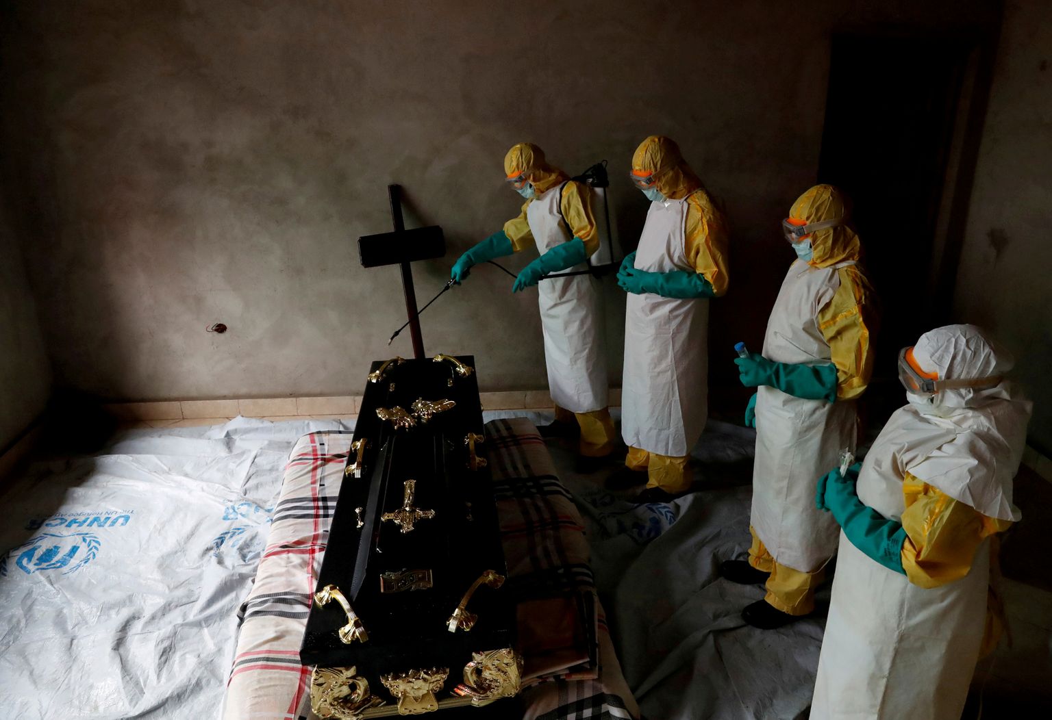 Mediķi dezinficē istabu un zārku, kurā atrodas persona, kas, iespējams, gājusi bojā no ebolas vīrusa.