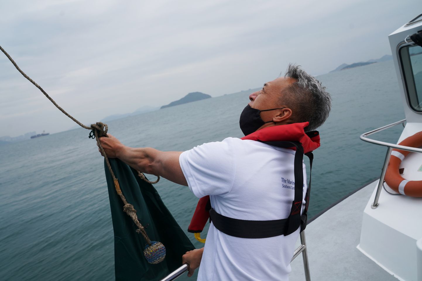 Hong Kong. Abiorganisatsiooni Mission of Seafarers töötaja saadab köie otsa seotud kotiga toiduaineid ja ravimeid laevale, millele lõksu jäänud meremehi sadamas maale varusid täiendama ei lubata.