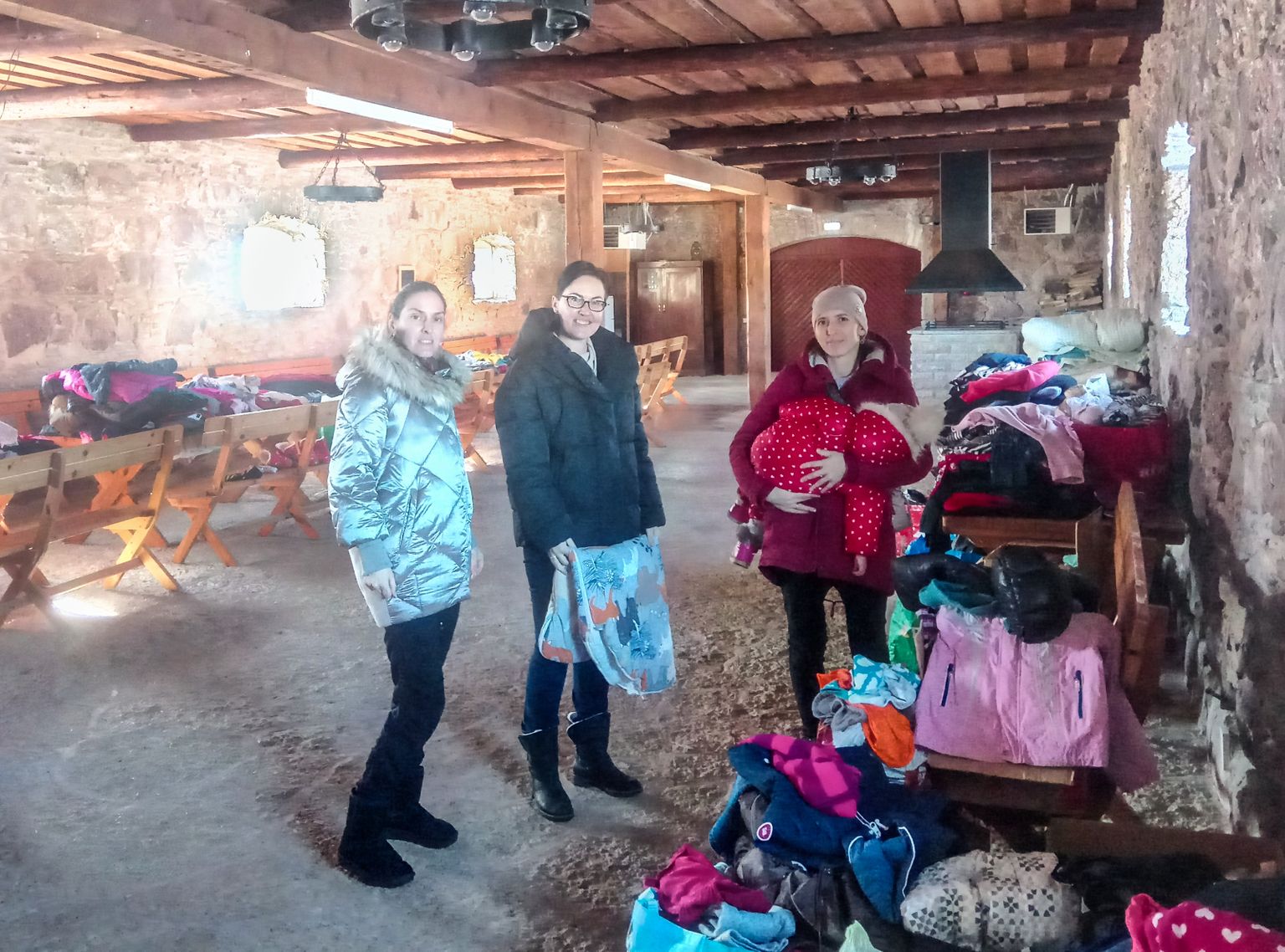 Sõjapõgenikud Olga Barabanova (vasakul) ja Larissa Sviridova jagavad Maidla mõisaaidas vabatahtlikena toidu- ja riideabi, parasjagu tuli selle järele Ukrainast Kiviõli Keemiatööstuses töötava abikaasa juurde pagenud Oksana.