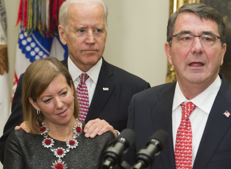 Meedias nüüdse skandaali ajal laialt jagatud foto 2015. aastast, kus esiplaanil on USA toonane kaitseminister Ash Carter ametisse vannutamise tseremoonial, taamal tema abikaasa Stephanie ja asepresident Joe Biden.