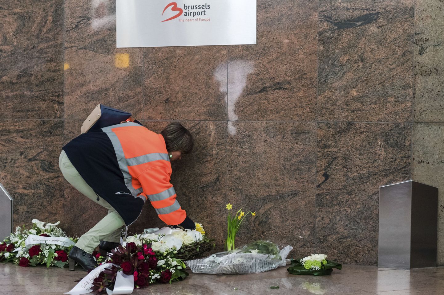 Brüsseli lennujaama töötaja mälestusmärgi ette lilli asetamas.
