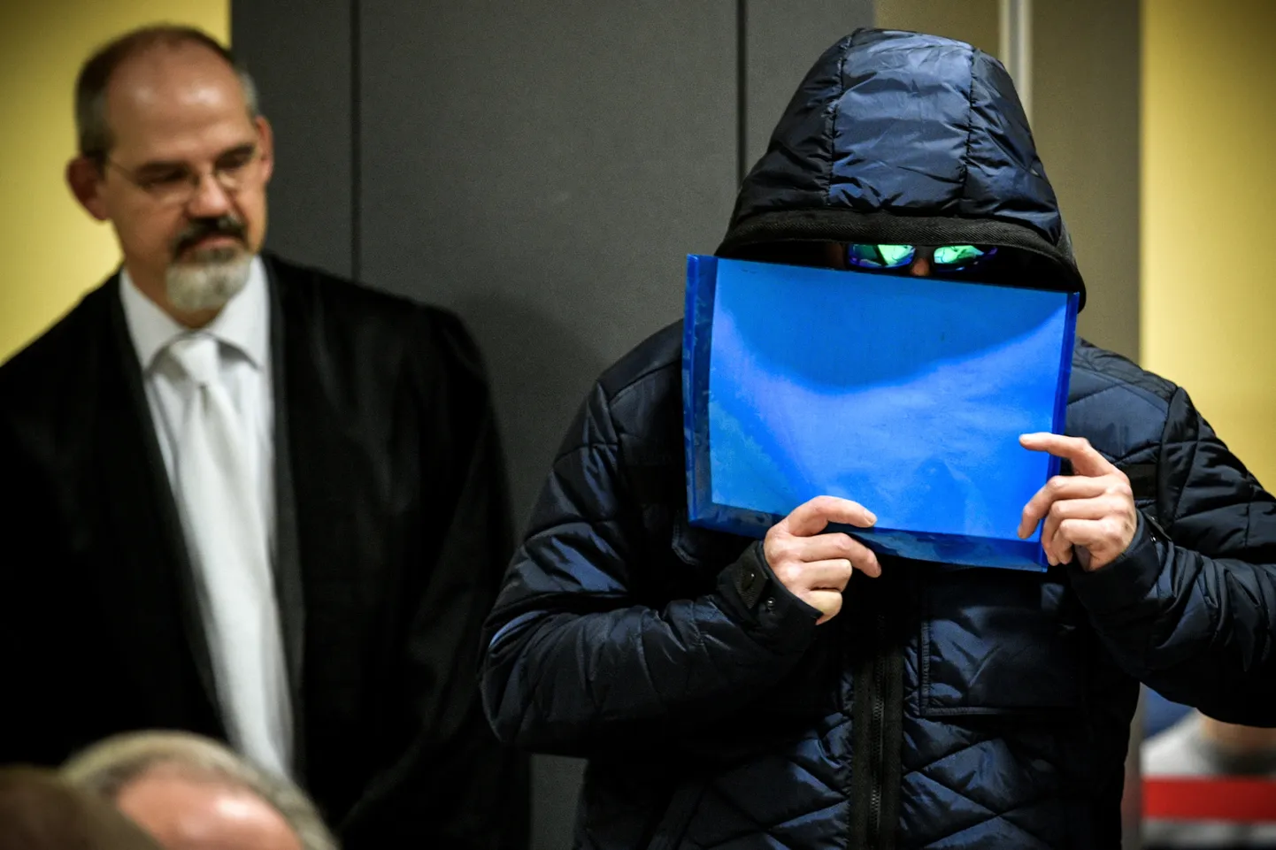 Siegeni konverentsikeskuses toimuvale protsessile saabuv süüdistav püüab oma nägu peita. Kokku 32 inimest süüdistatakse asüülitaotlejate julmas kohtlemises Burbachi põgenikekeskuses.