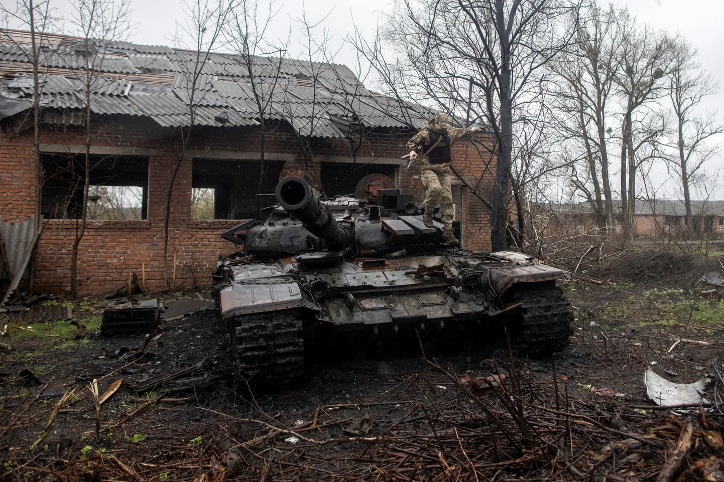 Украинский солдат прыгает из подбитого российского танка на окраине села Малая Рогань в Харьковской области. Украина, 20 апреля 2022. ФОТО: REUTERS/Alkis Konstantinidis