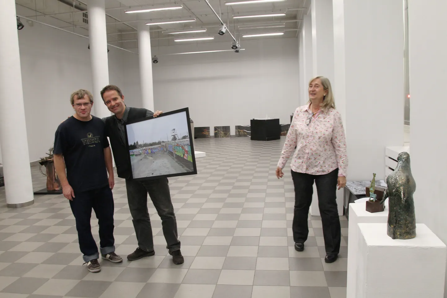 Manel Clemente näitab Andres Sütevaka kõrval seistes oma fotot. Merce Tiana vasakul käel on postamendi otsas tema keraamiline hobuse portree.