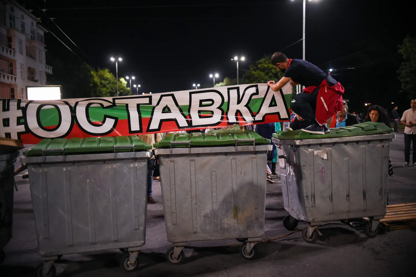 Meeleavaldaja äsja taaspüstitatud prügikastidest barrikaadil.