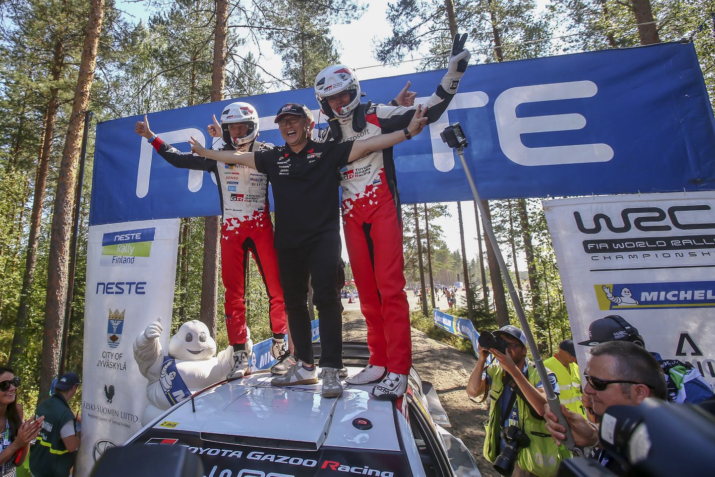 Akio Toyoda tähistamas koos Ott Tänaku ja Martin Järveojaga auto katusel Soome ralli võitu.