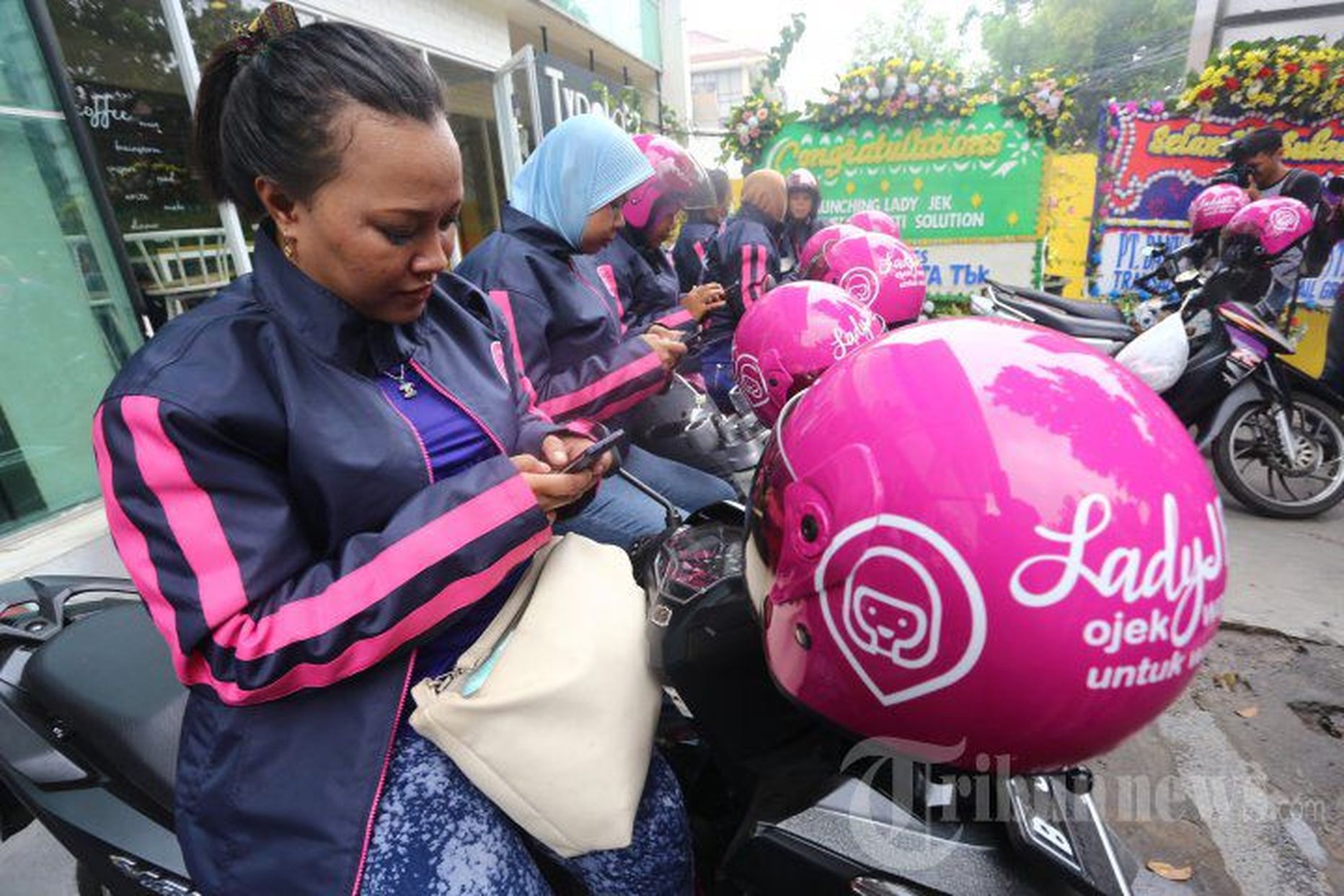 LadyJeki juhid Jakartas ojeki seljas kliente ootamas ja nutitelefoni näppimas.