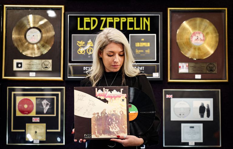 Londonas izsoļu nama "Bonhams" darbiniece tur rokā īpaši retu, oriģinālā grupas sastāva dalībnieku parakstītu "Led Zeppelin" 1969. gada albumu II, kurš 2023. gada novembrī tika pārdots par 2,625 sterliņu mārciņām.