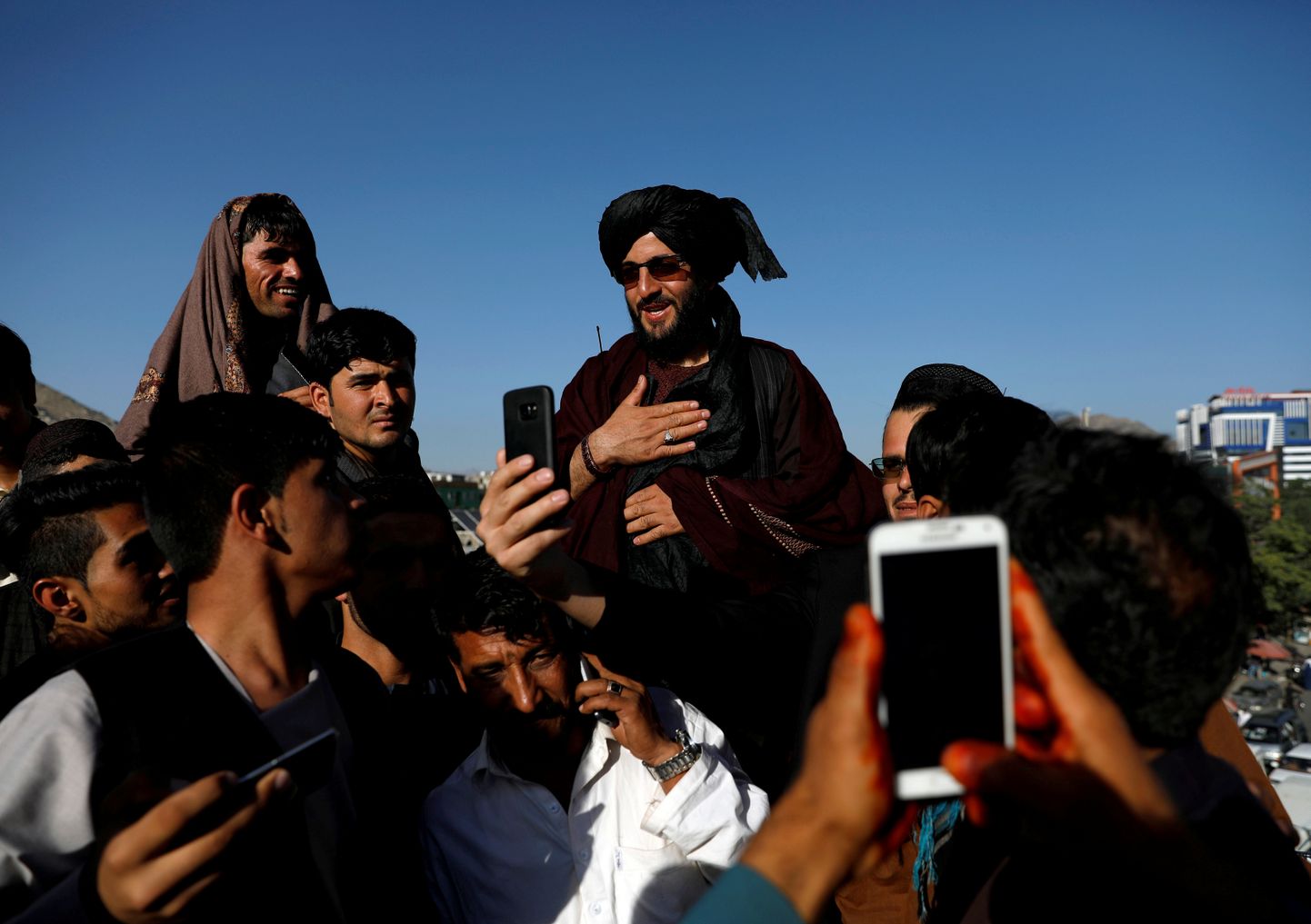 Inimesed teevad pilte Talibani liikmega.