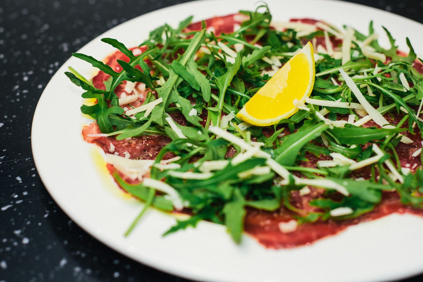 Beef carpaccio: starter based on raw beef, lemon, Parmesan olive oil and rocket