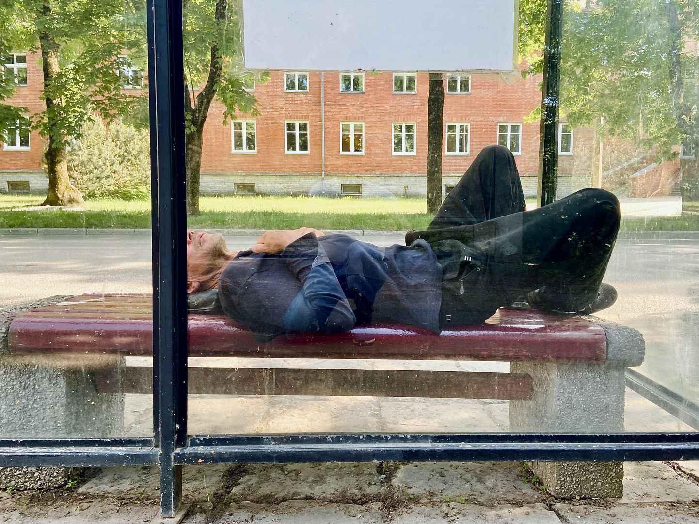 Бездомный спит на автобусной остановке в Нарве.