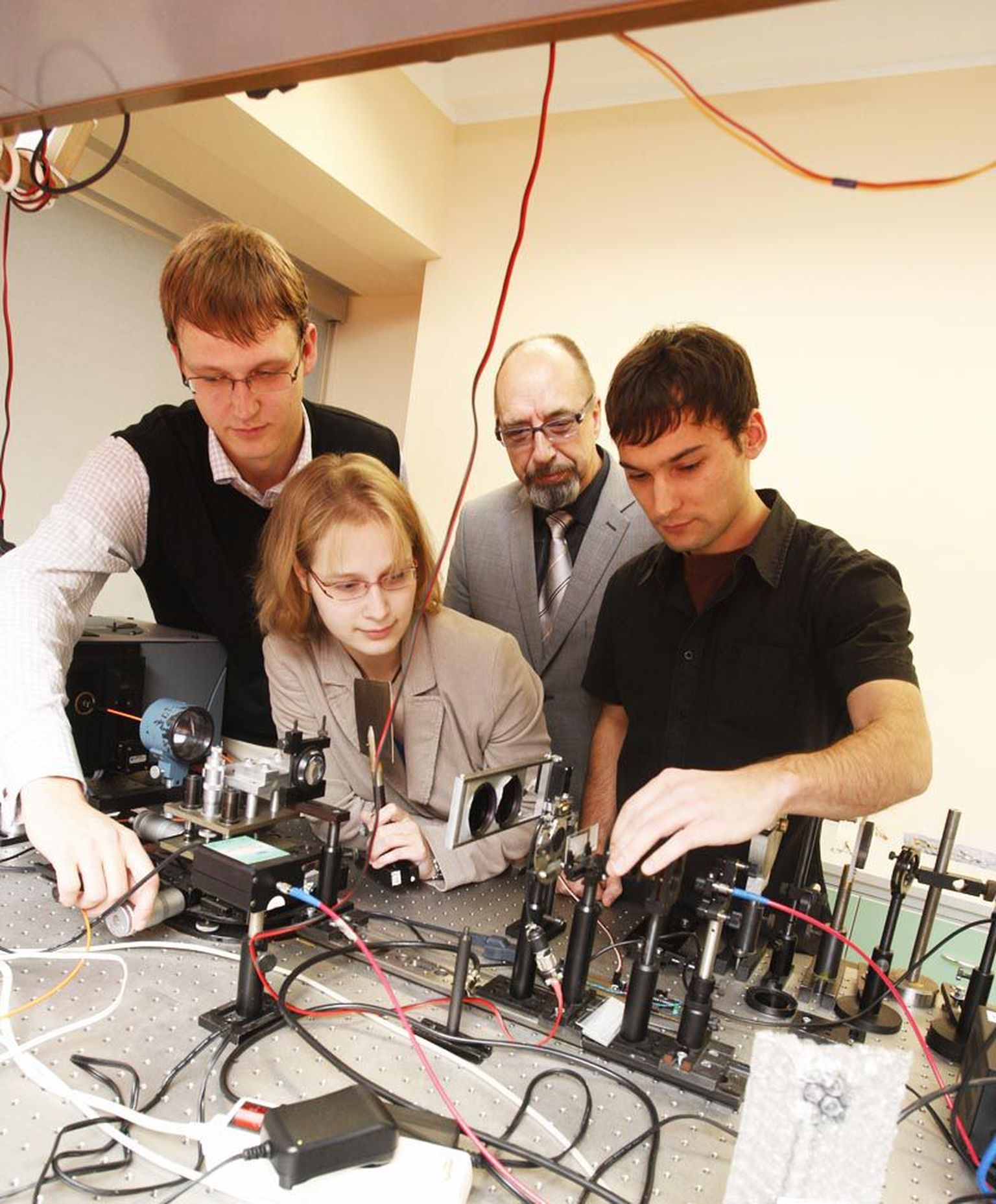 Akadeemik Peeter Saari (tagaplaanil ülikonnas) koos doktorantide Peeter Piksarve (vasakult) ja Heli Lukneri ning magistrant Madis Lõhmusega laboris.