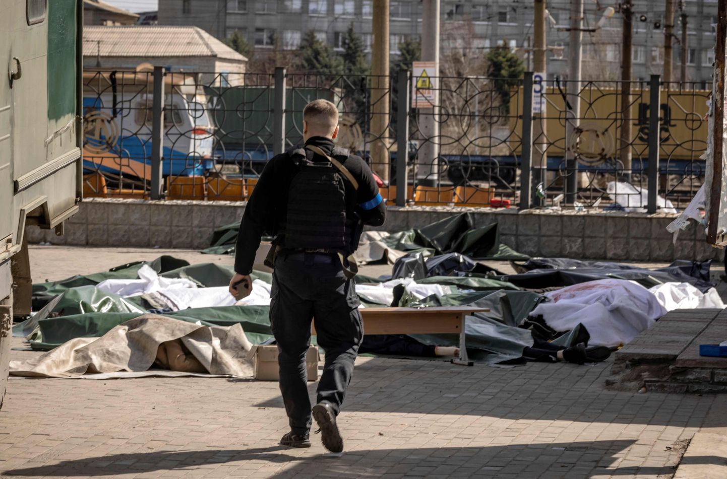 Украинский полицейский идет к телам, покрытым пленкой, после ракетного обстрела, унесшего жизни не менее 35 человек на вокзале в Краматорске (восточная Украина), который использовался для эвакуации гражданского населения. 8 апреля 2022 года. ФОТО: ФАДЕЛЬ СЕННА / AFP