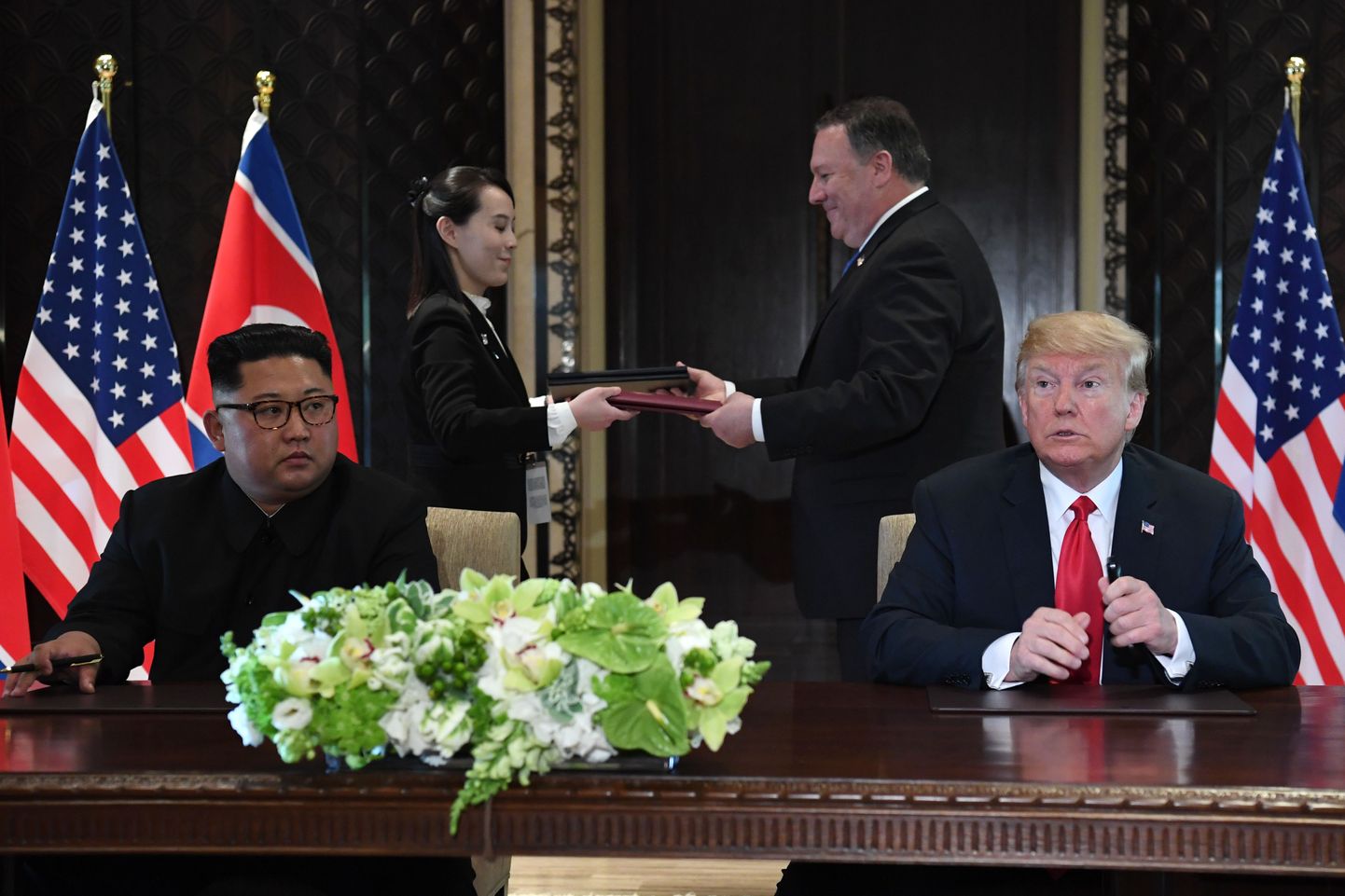 Donald Trump (paremal) ja Kim Jong-un. Taustal vahetavad dokumente USA välisminister Mike Pompeo ja Kimi õde Kim Yo-jong.