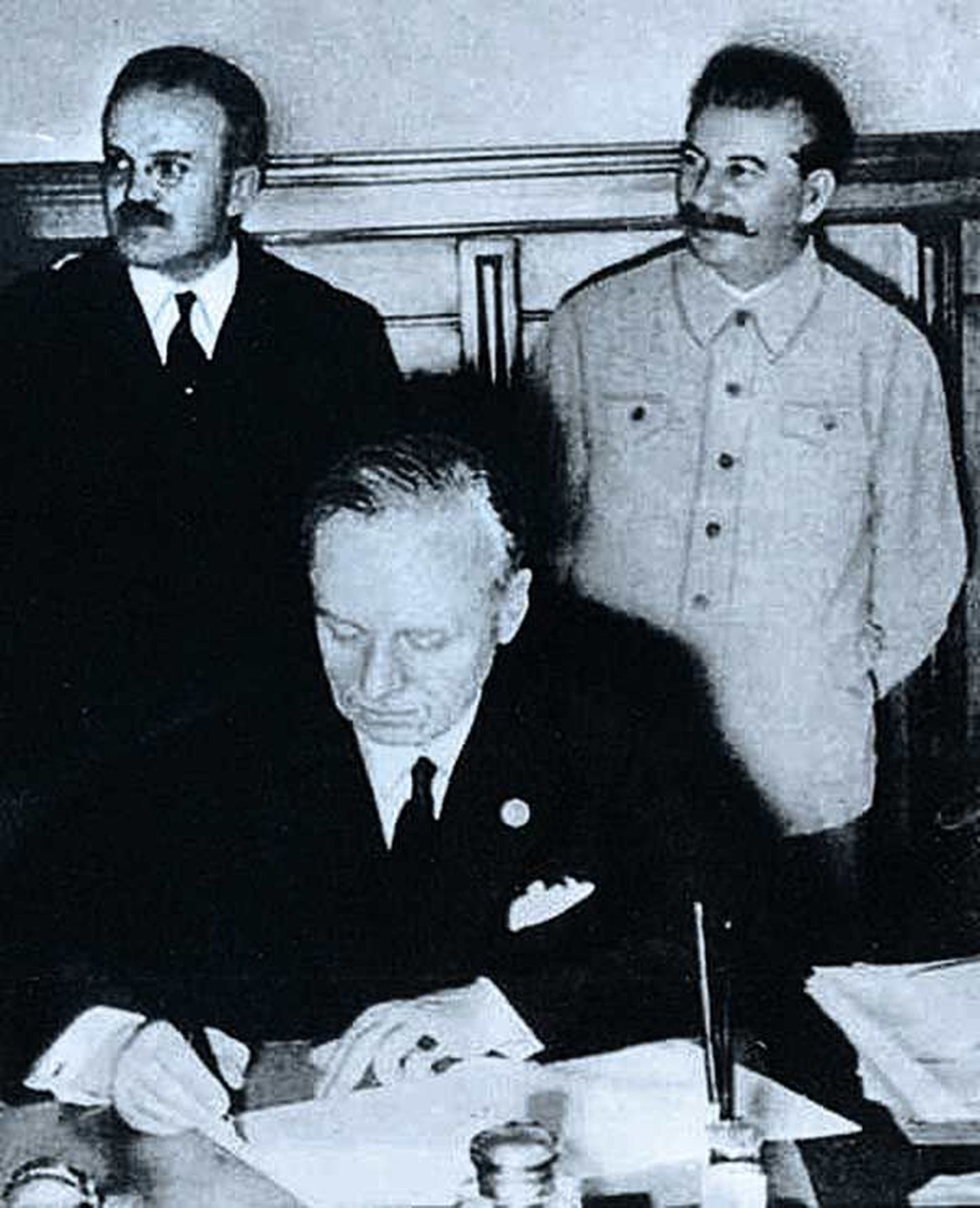 1939. aastal allkirjastatud Molotov-Ribbentropi pakt põhjustab ajaloolaste ja poliitikute erinevate tõlgenduste tõttu siiani segadust näiteks Balti riikide ja Venemaa suhetes. Pildil seisavad Vjatšeslav Molotov ja Jossif Stalin, allkirja annab Joachim von Ribbentrop.