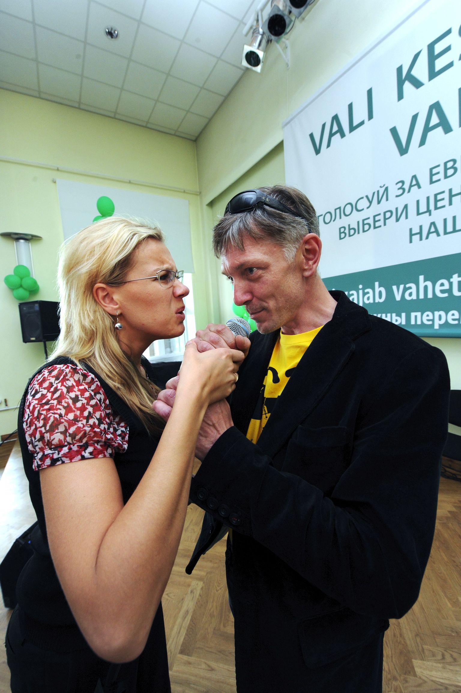 Indrek Tarand ja Kadri Must Keskerakonna valimispeol Salme kultuurikeskuses mikrofoni pärast kemplemas.