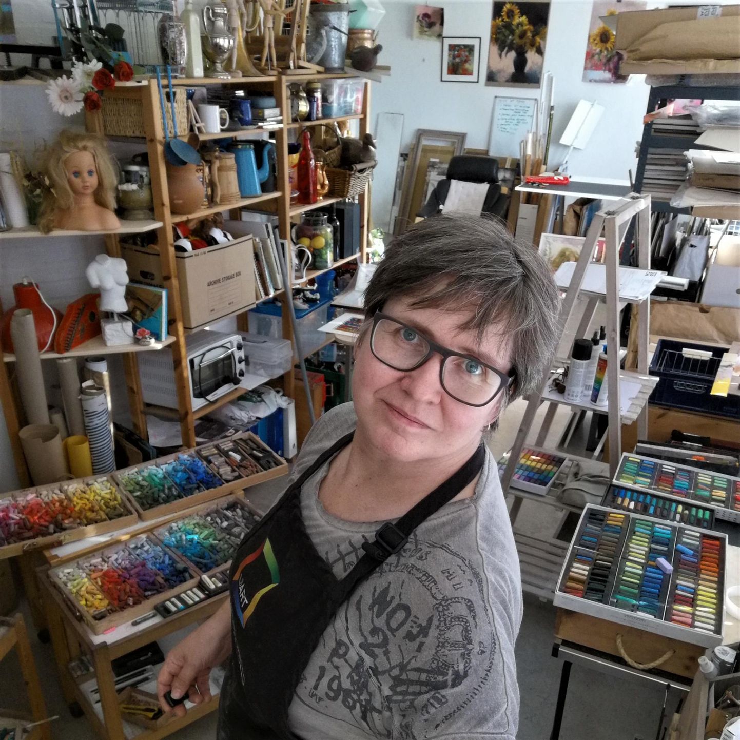 Silja Salmistu (53) pildistas ennast ateljees, kus tema paremal käel ja selja taga on pastellid.