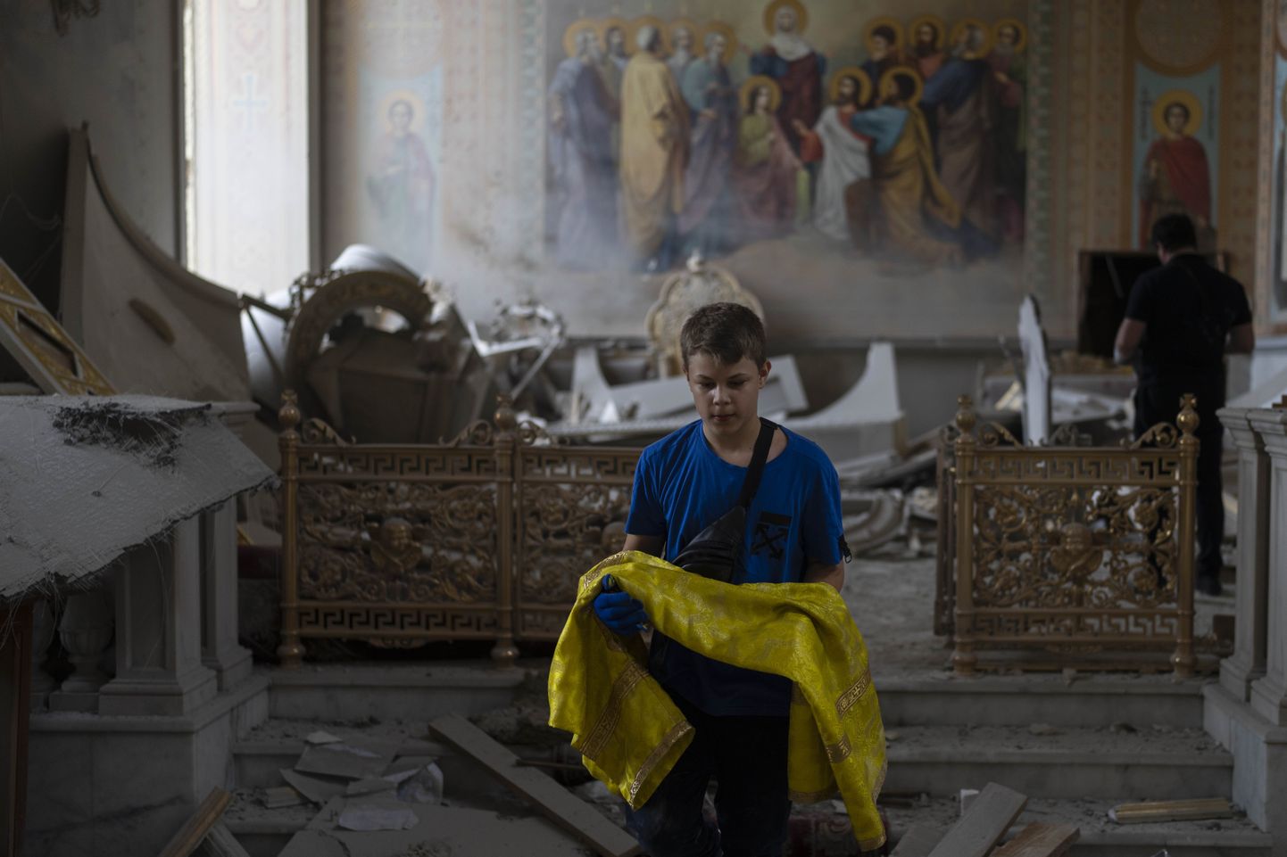 Украинский мальчик помогает спасать экспонаты из разбомбленного собора в центре Одессы.