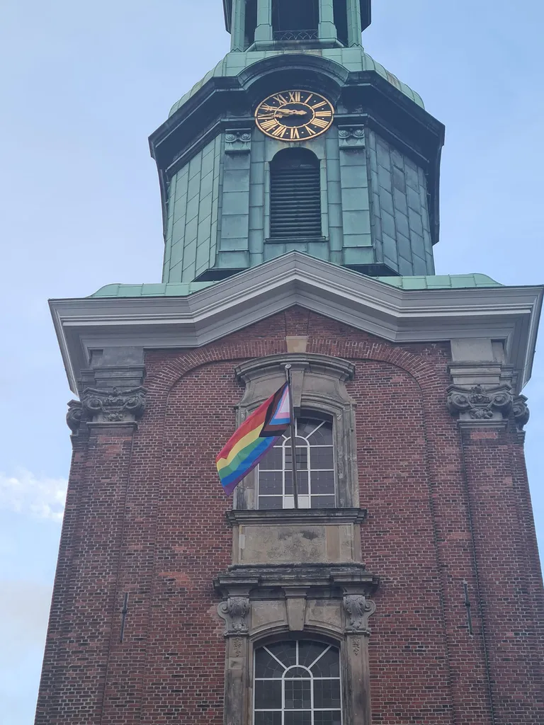 Флаг ЛГБТК+ сообщества на колокольне Церкви Святой Троицы в Гамбурге.