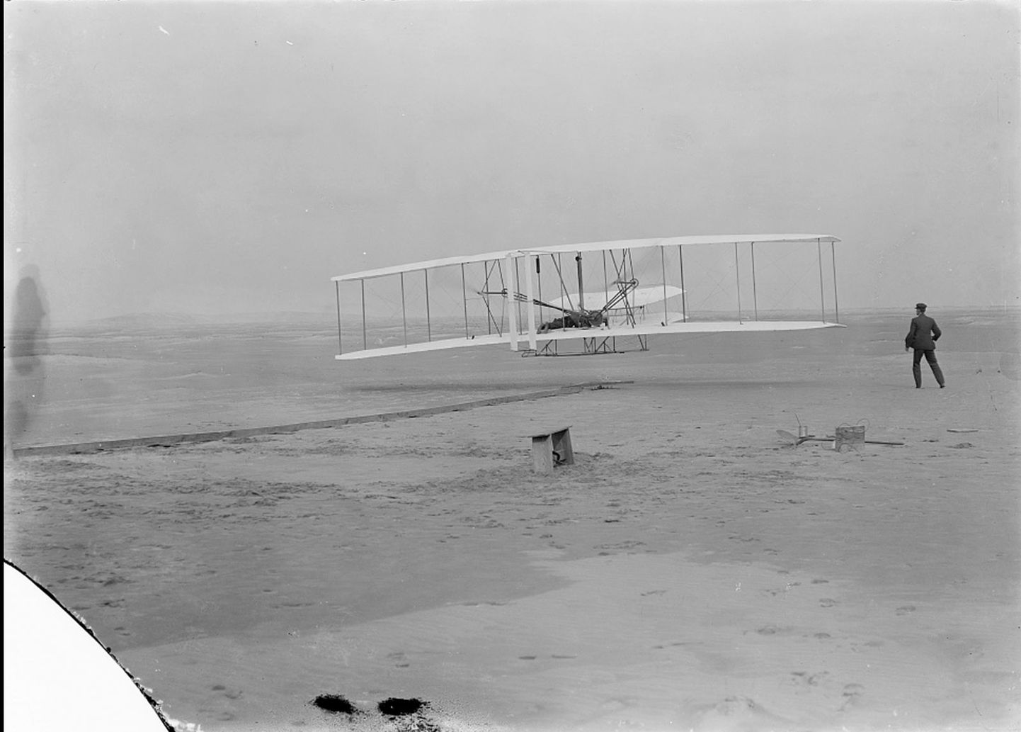 Orville Wright lendamas 17. detsembrl 1903 Põhja-Carolinas Kitty Hawki lähedal, tehes maailma esimese juhitava mootorlennu, olles õhus 12 sekundit ja läbides 36 meetrit. Lennuki juures on näha ka Wilbur Wrighti