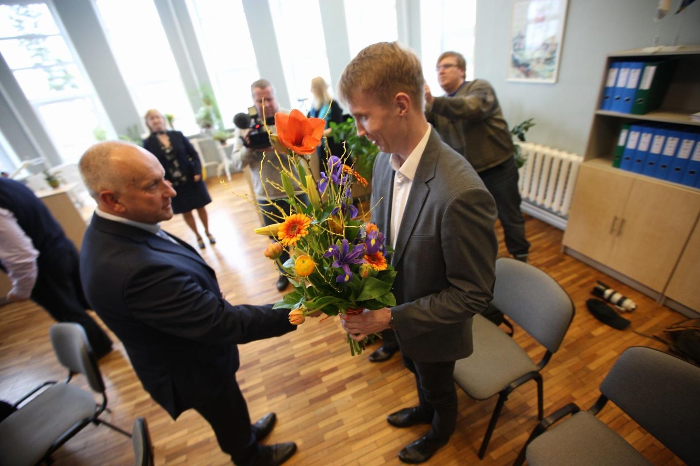 Volikogu esimeheks tagasi valitud Vello Väinsalu (vasakul) annab lilled vastsele vallajuhile Ivar Lillebergile.