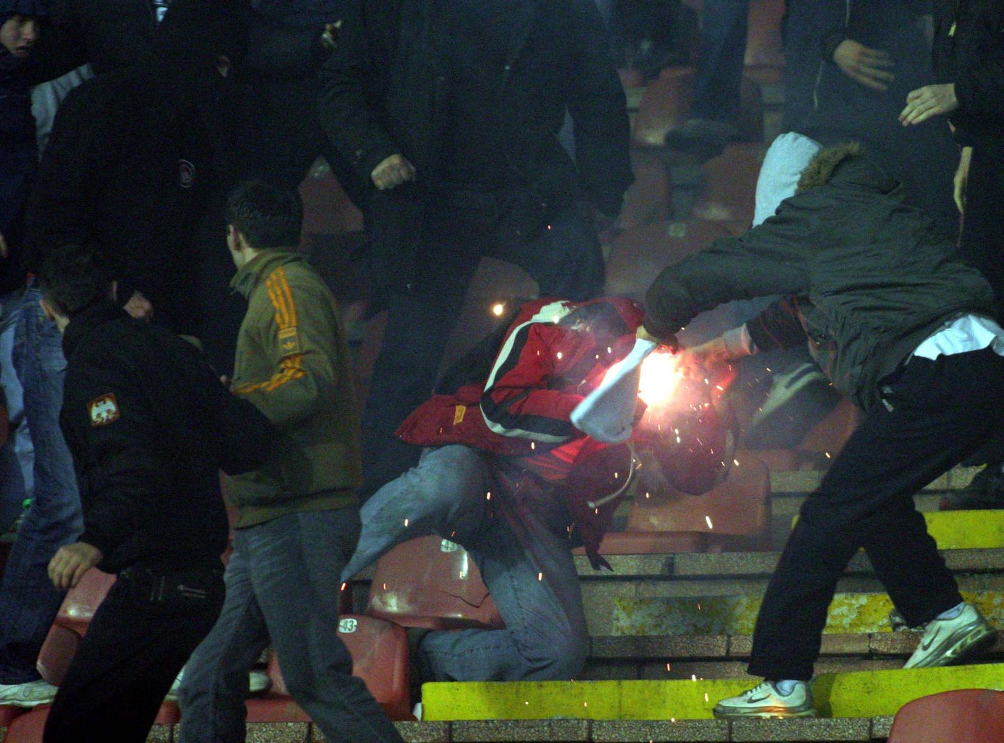 Belgradi jalgpallifännid ründamas politseinikku leegitseva signaaltõrvikuga.