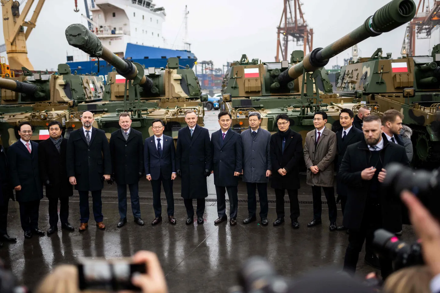 Poola president Andrzej Duda (vasakult kuues) ja kaitseminister Mariusz Blaszczak (vasakult neljas) poseerimas delegatsiooniga Soulist esimeste Lõuna-Korea lahingutankide üleandmise tseremoonial Gdynia konteineriterminalis 6. detsembril 2022.