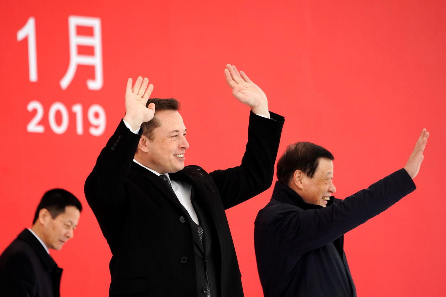Tesla tegevjuht Elon Musk (keskel) ja Shanghai linnapea Ying Yong (paremal) 7. jaanuaril 2019 Tesla tehase nurgakivi panemise tseremoonial rahvale lehvitamas.