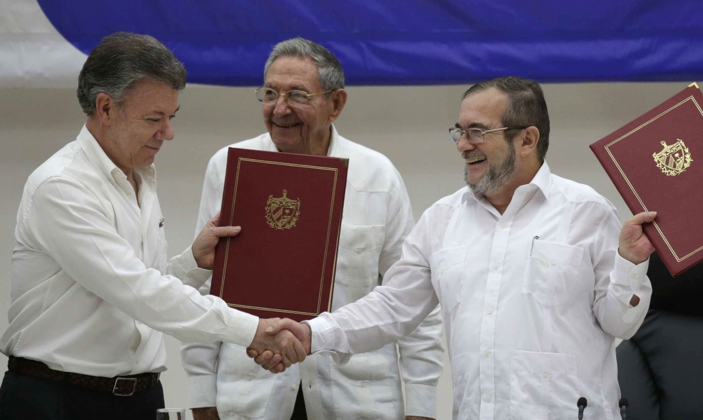 Colombia president Juan Manuel Santos (vasakul) ja FARC-i liider Timoleon Jimenez (paremal) surumas kätt relvarahu allkirjastamise tseremoonial.