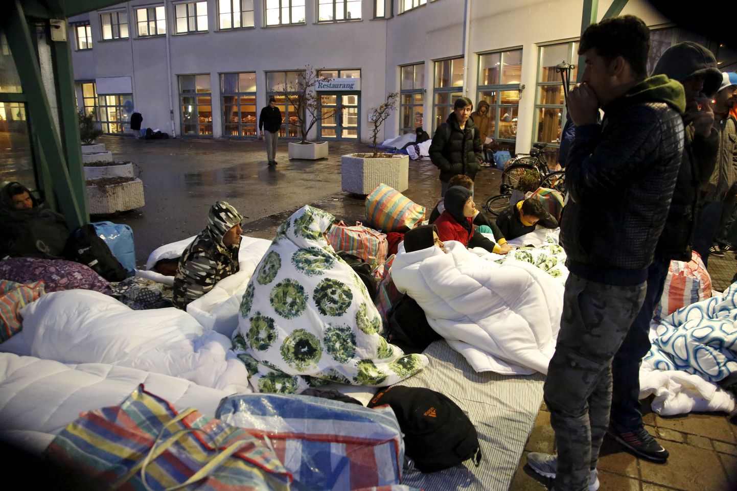 Refugees sleep outside the entrance of the Swedish Migration Agency's arrival center for asylum seekers at Jagersro in Malmo, Sweden, November 20, 2015. Sweden, a favourite destination for refugees flooding into Europe, can no longer house all those arriving and many will have to find their own accommodation, the country's migration agency said on Thursday. Sweden has already imposed temporary border controls in response to the record influx of refugees, while authorities plan to shelter thousands of people in heated tents as well as venues such as ski resorts and a theme park. REUTERS/Stig-Ake Jonsson/TT News Agency    ATTENTION EDITORS - THIS IMAGE WAS PROVIDED BY A THIRD PARTY. FOR EDITORIAL USE ONLY. NOT FOR SALE FOR MARKETING OR ADVERTISING CAMPAIGNS. THIS PICTURE IS DISTRIBUTED EXACTLY AS RECEIVED BY REUTERS, AS A SERVICE TO CLIENTS. SWEDEN OUT. NO COMMERCIAL OR EDITORIAL SALES IN SWEDEN. NO COMMERCIAL SALES.