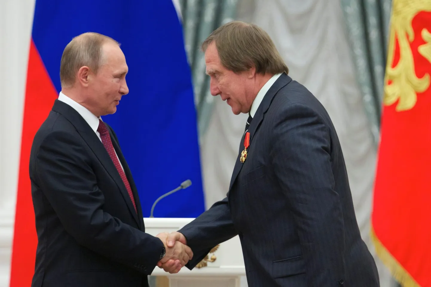 Президент России Владимир Путин жмет руку Сергею Ролдугину, которого считают теневым лицом прокрутки денег близкого окружения российского президента.