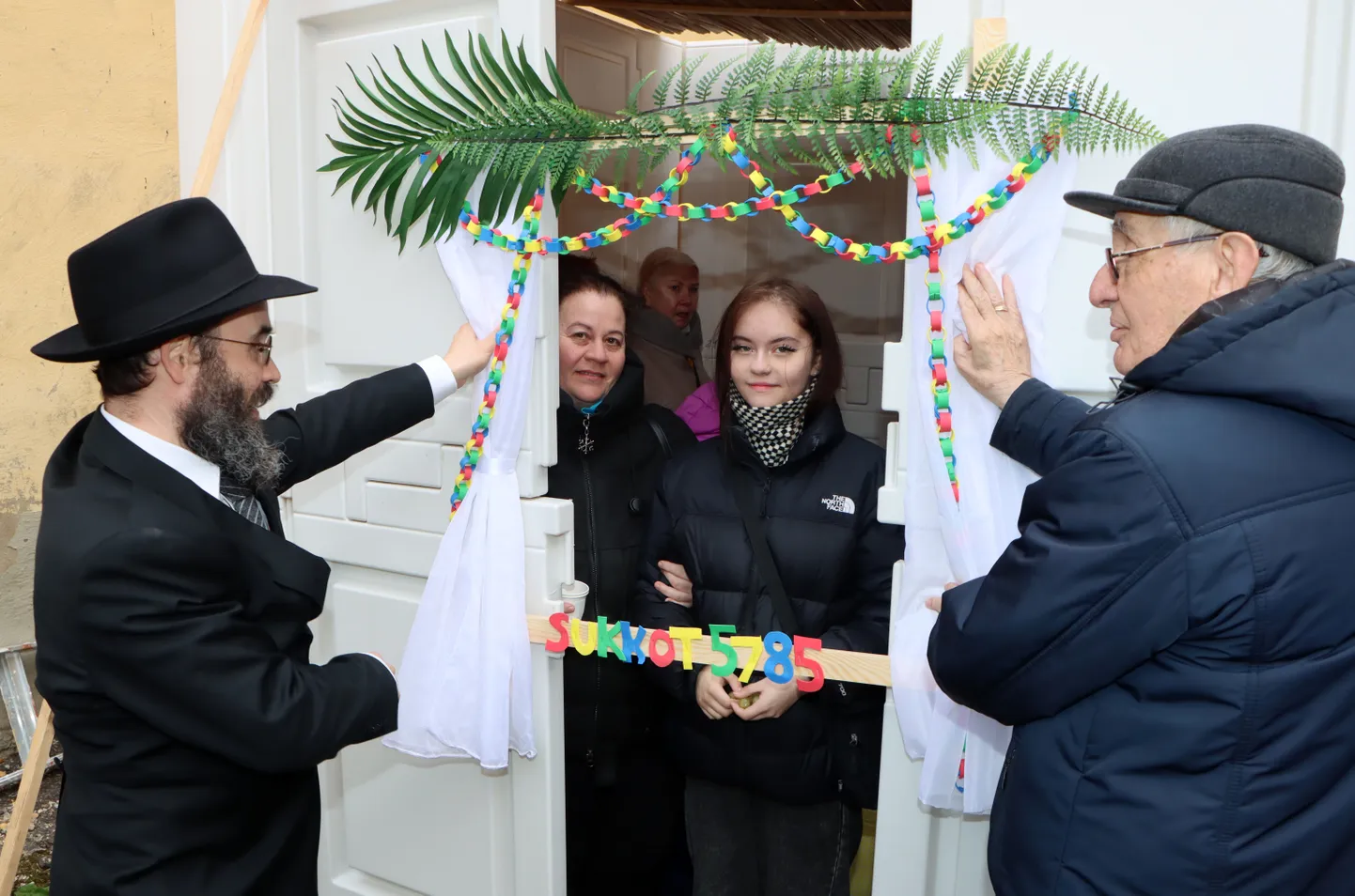 Pearabi Shmuel Kot ja Ida-Virumaa juudi kogukonna liider Aleksandr Dusman hoiavad lehtmaja sissepääsu kohal pildiraami − nõnda kaunistatakse lehtmaju ka Iisraelis.