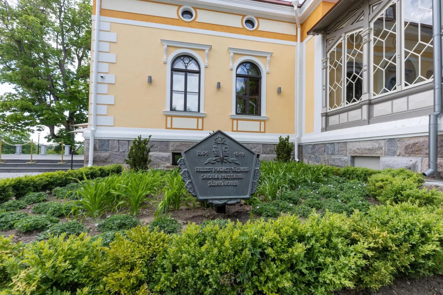 Varem kunagise Viljandi mõisa hoone seinal olnud mälestustahvlid leiab nüüd maja sissekäigu kõrvalt lillepeenrast. Üks asub ühel, teine teisel pool peaust.