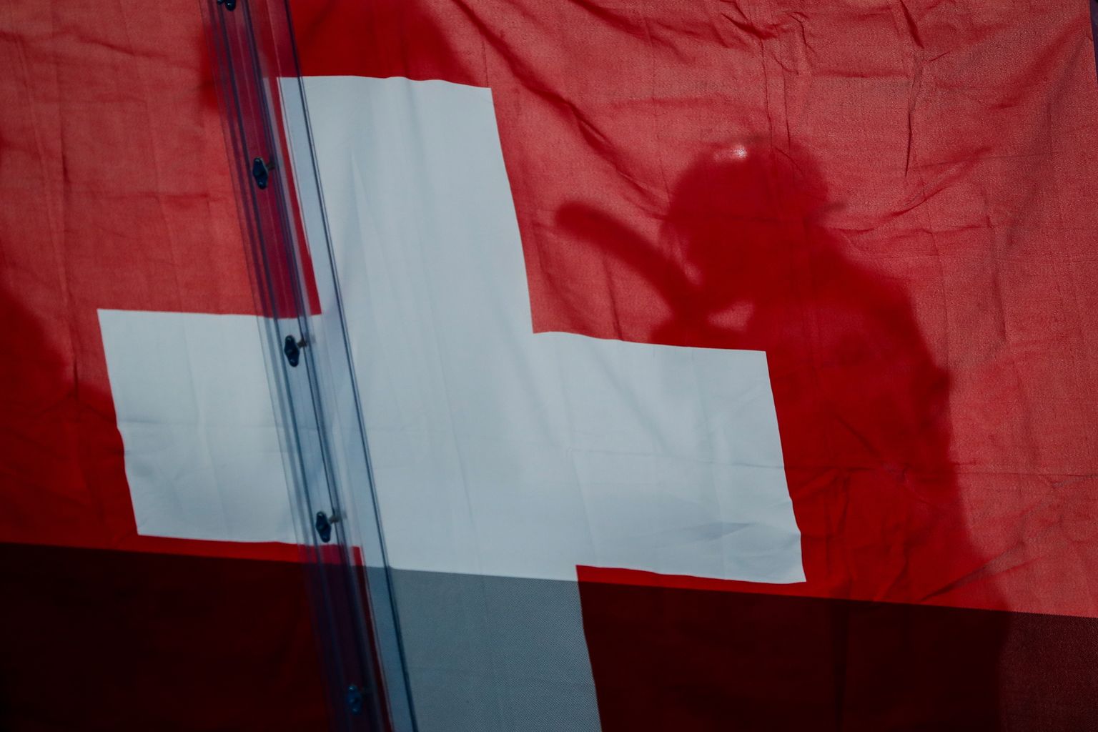 Šveitsi lipp ja jäähokimängija. Foto on illustratiivne.