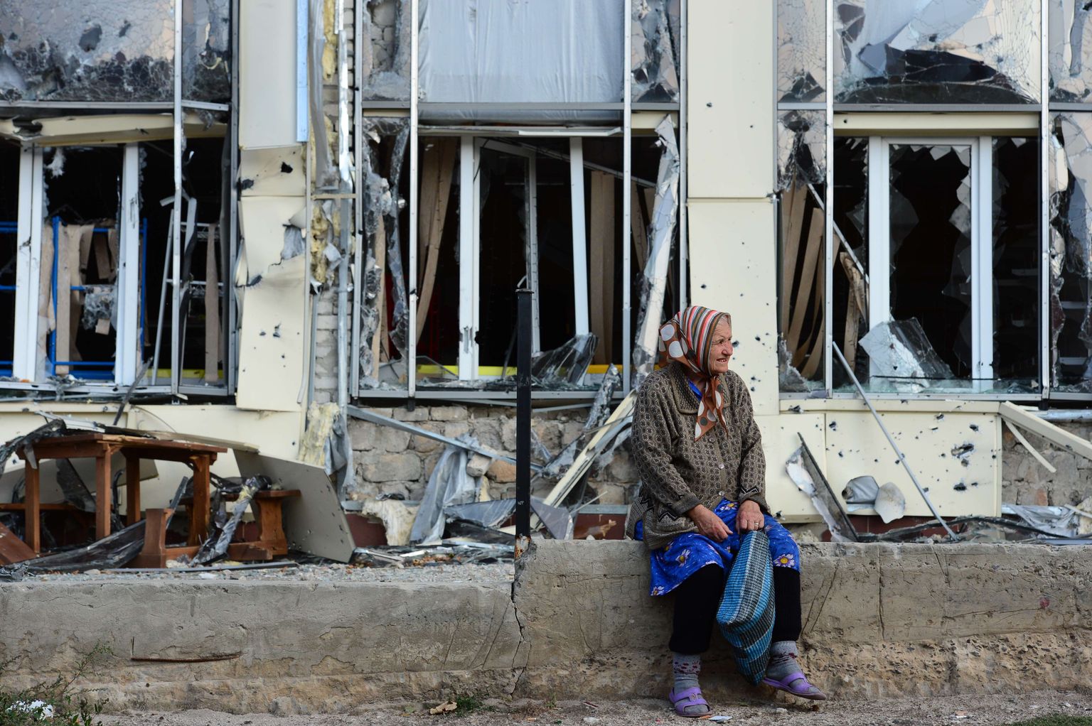 Eakas naine puhkamas jalgu sõjast räsida saanud hoone ees Pervomaiskis Ida-Ukrainas.