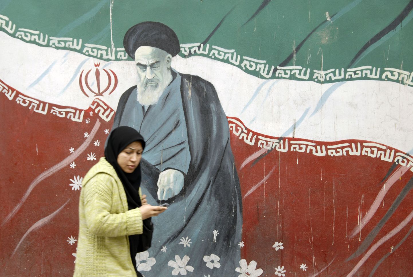 Naine möödumas seinamaalingust, kus on kujutatud Iraani Islamistliku Vabariigi ühte rajajat ajatolla Khomeinit.