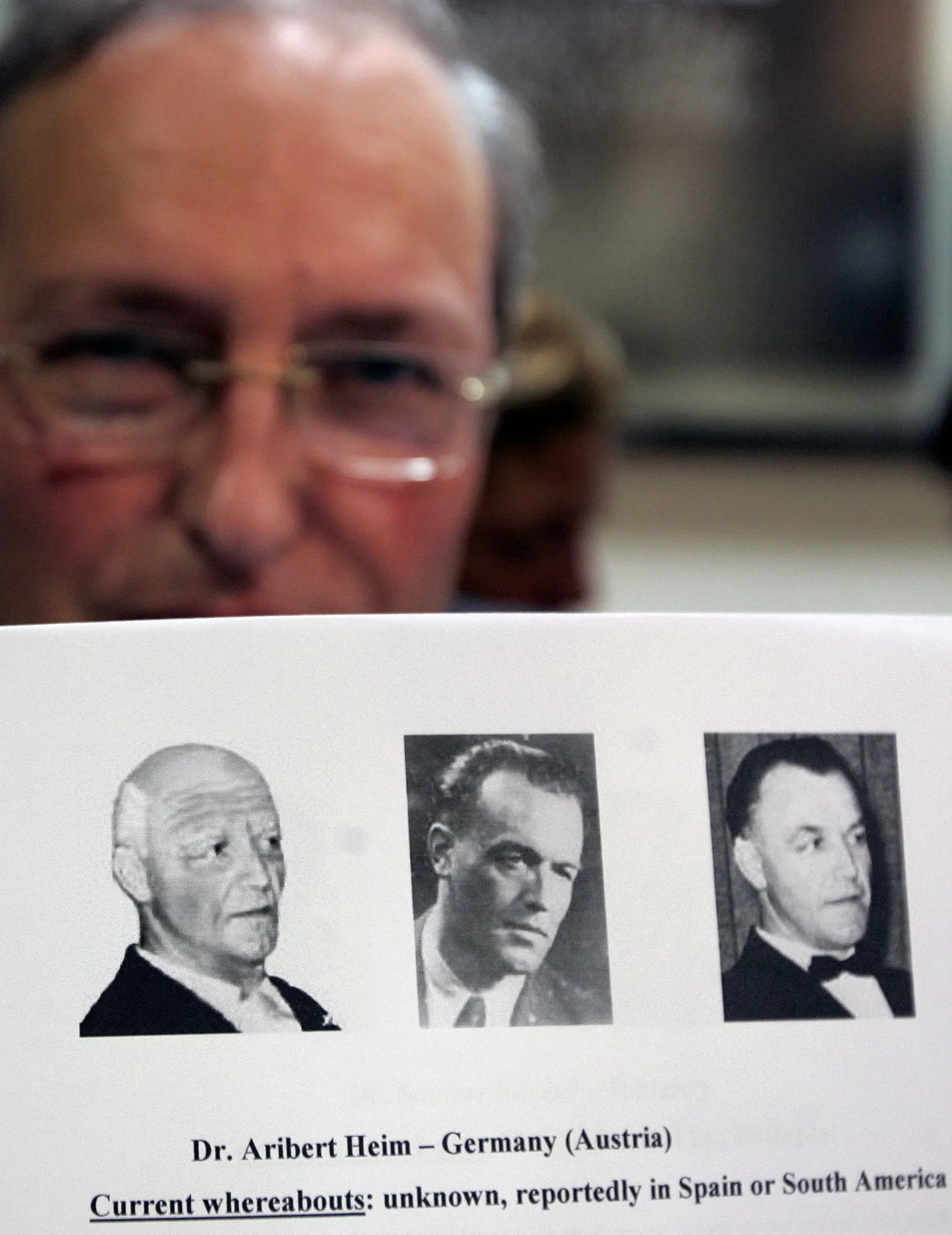 Efraim Zuroff näitab fotosid Aribert Heimist. Üks neist on arvutijoonis, milline ta võis vanas eas välja näha