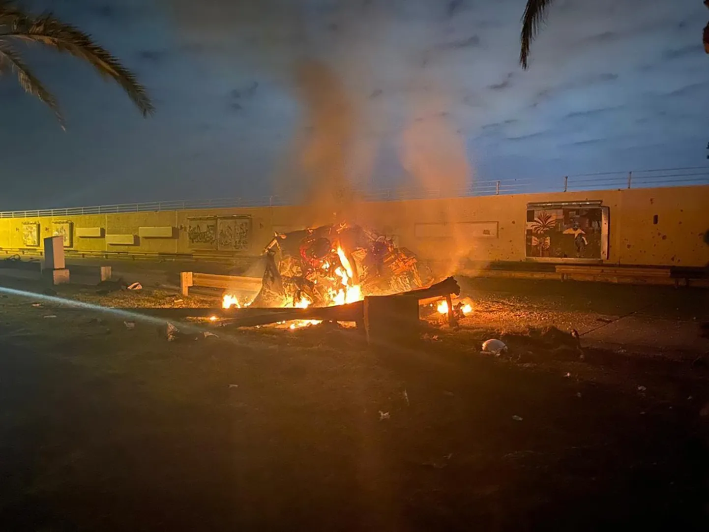 Irākas valdības publicēts foto ar degošu automobili pēc raķešu uzbrukuma Bagdādes lidostā.