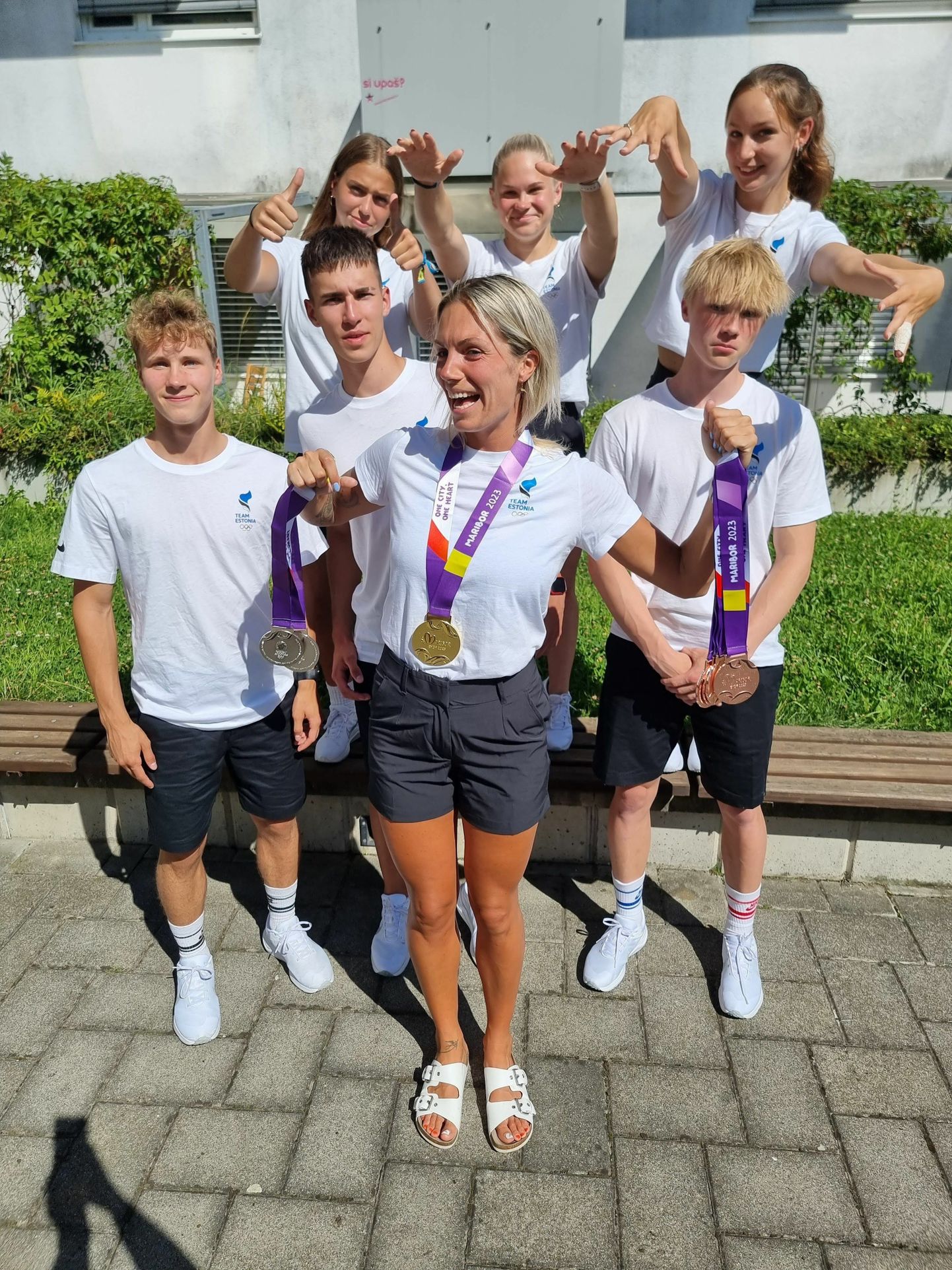 Liisi Sakala (ees keskel) noorte olümpiafestivalil poseerimas koos sportlaste ja nende medalitega.