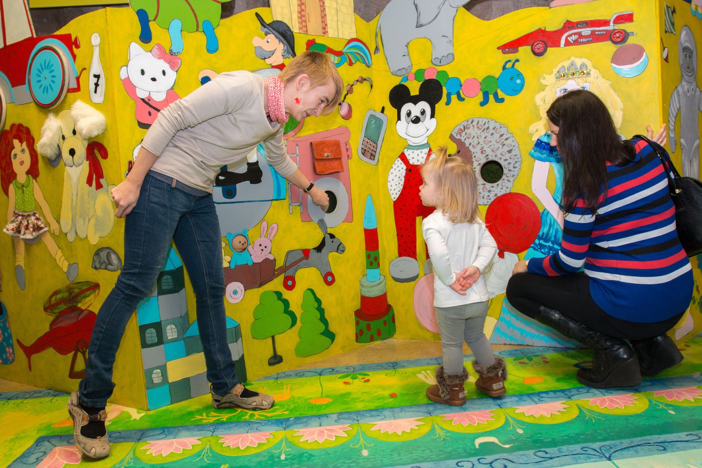 Väike Isabel uurib koos ema Merlin Jänese (paremal) ja mänguasjamuuseumi töötaja Marge Pärnitsaga, mis põnevad asjad on seina taga varjul.